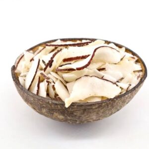 Dried coconut chips inside a coconut shell used as a bowl. white background.